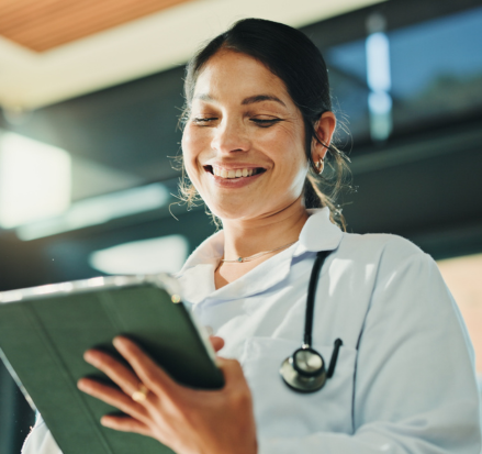 Médica sorrindo enquanto utiliza tablet para consultar informações médicas.