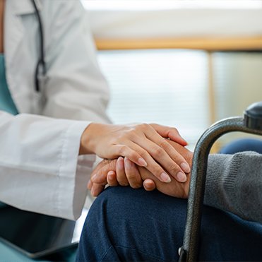 Médica segura a mão de paciente em gesto de acolhimento durante consulta.
