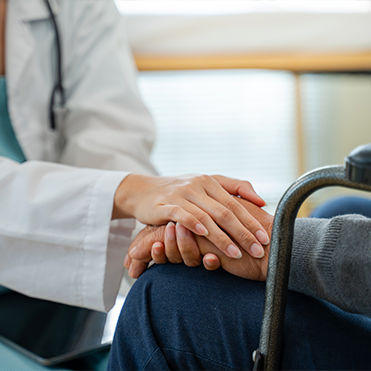 Médica segura a mão de paciente em gesto de acolhimento durante consulta.