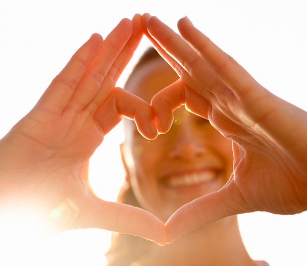 Pessoa formando coração com as mãos em gesto de cuidado e carinho.